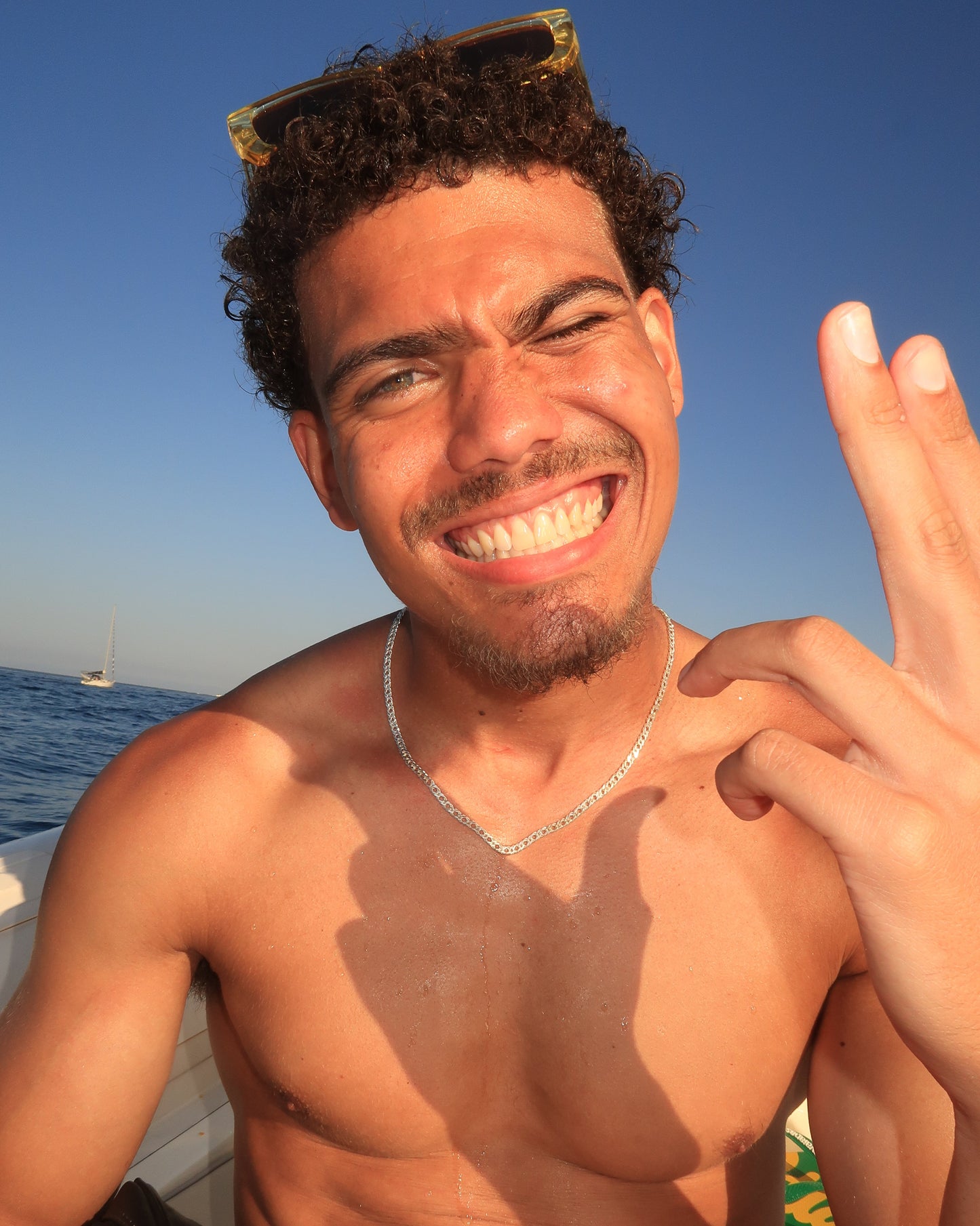 Man with sunglasses on head, smiling outdoors with clear blue sky wearing a double cuban 925 sterling silver necklace