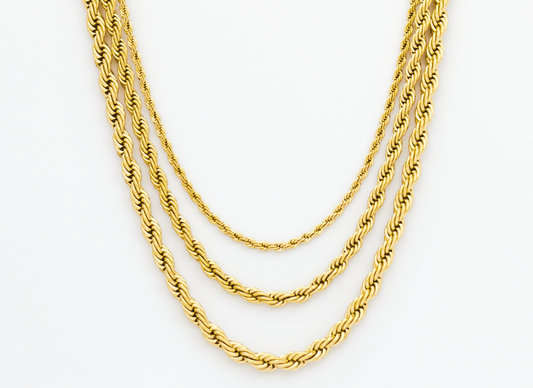 Three gold necklaces of different thicknesses on a white background